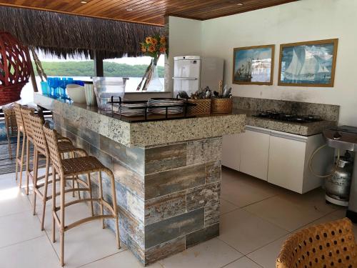 a kitchen with a counter with chairs and a refrigerator at Casa praia Porto de Galinhas Toquinho in Ipojuca