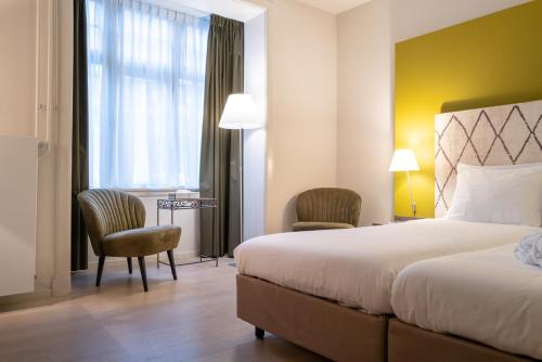 a hotel room with a bed and chairs and a window at Hotel Au Quartier in Maastricht
