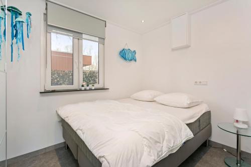 Una habitación blanca con una cama y una ventana en Vakantiehuis Zee, Bos & Duin Zoutelande ZO01, en Zoutelande