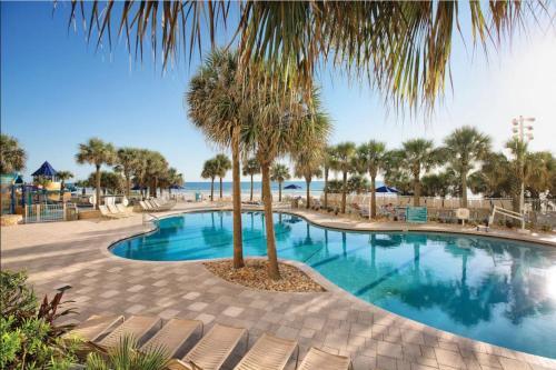 a swimming pool with chairs and a palm tree at Beachfront Bliss at Ocean Walk Resort - Unit 1701 in Daytona Beach