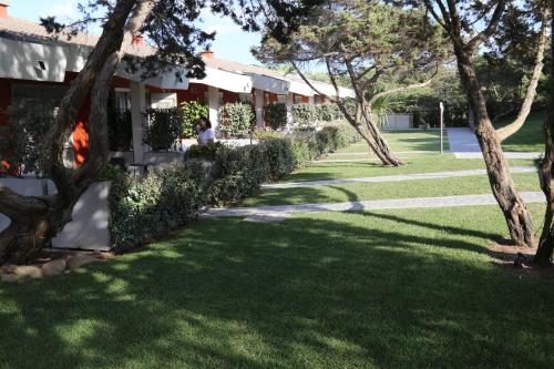 a grassy yard with trees and a building at Club Esse Sporting in Stintino