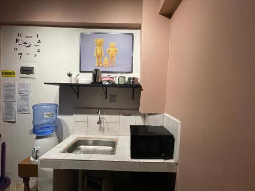 a small kitchen with a sink and a microwave at Staycation Cozy Comfortable STAY Hotel QualitY fast Internet Worldwide Channel Cable TV Gaming Netflix Sanitize in Manila