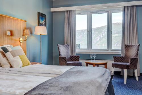 エイドフィヨルドにあるVøringfoss Hotelのベッド1台、椅子2脚、窓が備わる客室です。