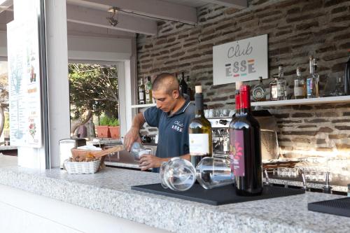 a man preparing food at a counter with wine bottles at Club Esse Sporting in Stintino