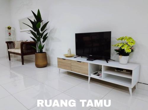 a living room with a flat screen tv on a entertainment center at OneFamily Homestay in Kuala Terengganu