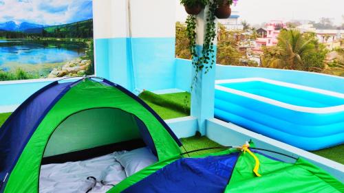 a green and blue tent on a balcony with a view at Cupidtrails Backpacker's Penthouse in Guwahati