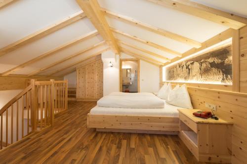 een slaapkamer met een bed in een kamer met houten vloeren bij Aktiv Hotel Schönwald in Nova Levante