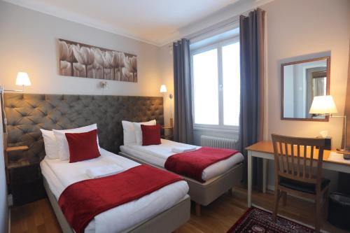 a hotel room with two beds and a desk at Park Hotell in Kristinehamn