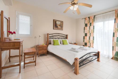 a bedroom with a bed with a ceiling fan and a desk at Resitour - Limnaria Gardens in Paphos City