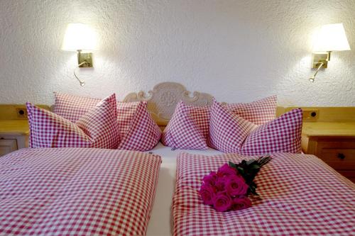two beds with pink and white pillows with a rose at Hotel Maier zum Kirschner in Rottach-Egern