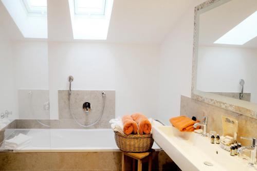 a bathroom with a sink and a tub with a mirror at Hotel Maier zum Kirschner in Rottach-Egern
