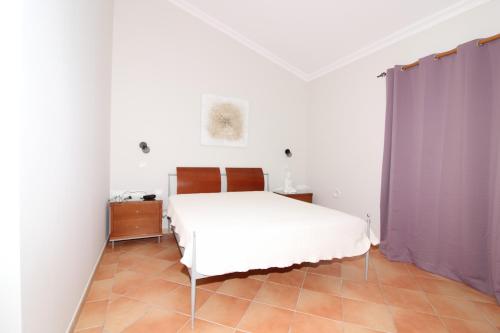 sypialnia z białym łóżkiem i fioletowymi zasłonami w obiekcie Villa Martina - São Rafael - Albufeira w Albufeirze