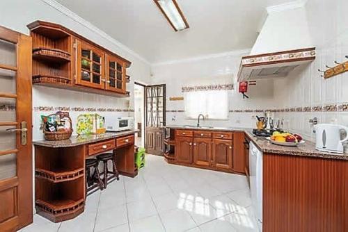 une grande cuisine avec des armoires et des appareils en bois dans l'établissement Villa Vista Mar - Galé - Albufeira, à Guia