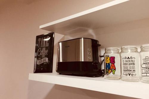 a shelf with a coffee maker and jars on it at Bonito Departamento a metros del MAR . in Puerto Madryn