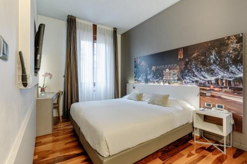 a bedroom with a large white bed and a desk at Hotel Giulietta e Romeo ***S in Verona