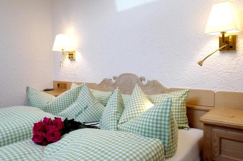 a bedroom with two beds with green and white pillows at Hotel Maier zum Kirschner in Rottach-Egern