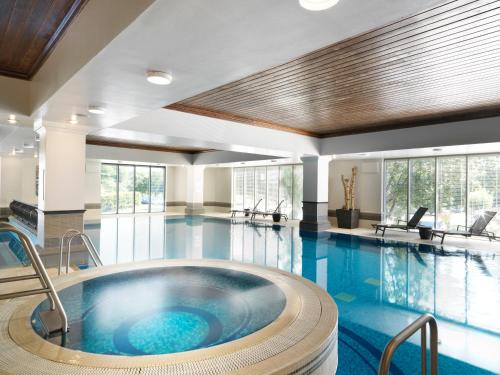 uma grande piscina com uma banheira de hidromassagem num edifício em The Runnymede on Thames em Egham