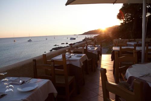 a restaurant with tables and chairs and the ocean at Club Esse Shardana in Santa Teresa Gallura