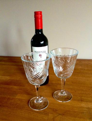 a bottle of wine and two wine glasses on a table at Bed and Breakfast De Paalberg in Hoenderloo