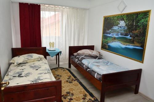 two beds in a room with a painting on the wall at Hostel GeAS I in Caransebeş