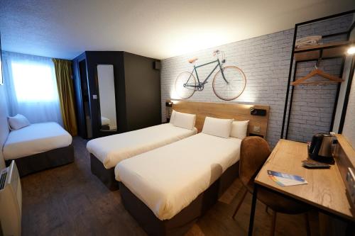 a hotel room with two beds and a bike on the wall at Kyriad Hotel Laval in Laval