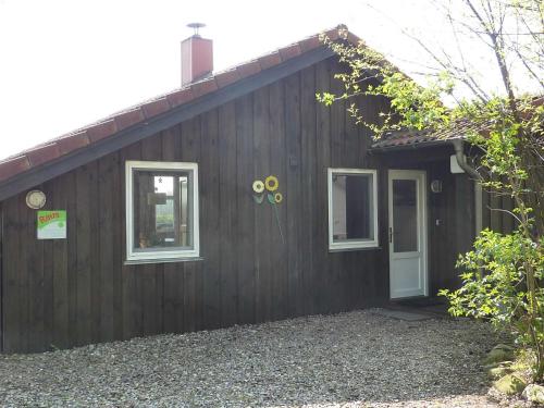 a brown house with two windows and a door at Ferienhaeuser Abild - Urlaub auf dem Bauernhof in Tarp