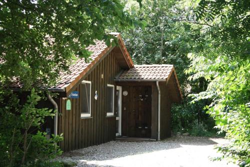 um pequeno barracão de madeira com uma porta na floresta em Ferienhaeuser Abild em Tarp