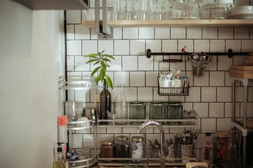 a kitchen with a sink and a tiled wall at J Poshtel Chiangmai in Chiang Mai