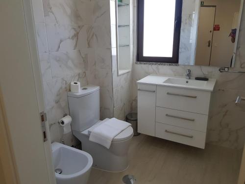 a white bathroom with a toilet and a sink at Forte Beach- Albufeira in Albufeira