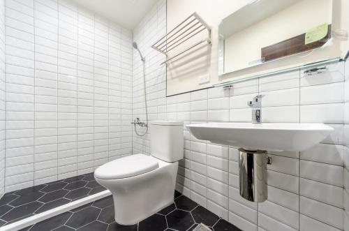 a white bathroom with a toilet and a sink at The Lin Inn in Kenting