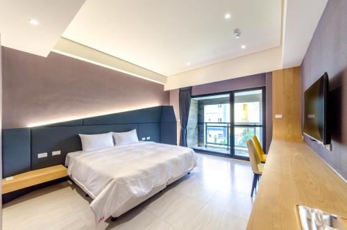 a bedroom with a bed and a flat screen tv at The Lin Inn in Kenting