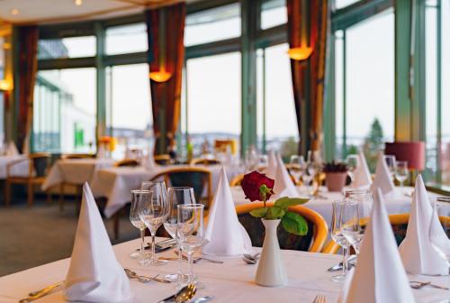 ein Esszimmer mit Tischen, weißen Servietten und Weingläsern in der Unterkunft Hotel Am Kurpark in Brilon