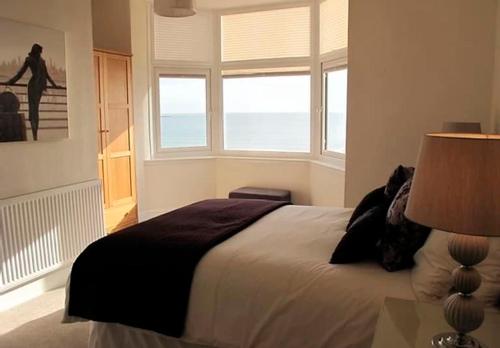 Un dormitorio con una cama y una ventana con el mar. en Ivy House - Seafront house with garden seating and stunning sea views! - Ocholo Villas, en Filey