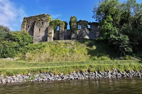 an old castle on a hill next to a river at River view cottage, in Cockermouth center in Cockermouth