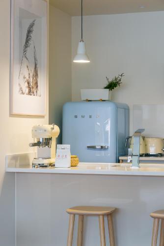 a kitchen with a counter with stools and a blue refrigerator at Three House Hotel in Funchal