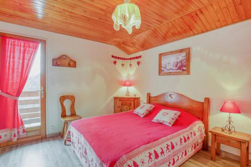 1 dormitorio con cama roja y techo de madera en Les Clarines - 3 chambres et jardin - magnifique vue en La Giettaz