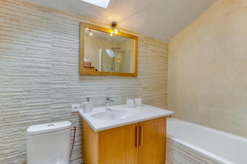 bagno con lavandino, servizi igienici e specchio di Les Clarines - 3 chambres et jardin - magnifique vue a La Giettaz