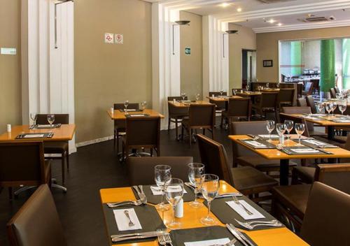 a dining room with tables and chairs with wine glasses at Estanplaza International in Sao Paulo