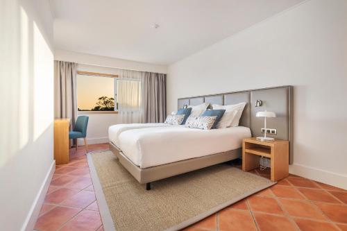 a bedroom with a bed and a desk and a chair at The Patio Suite Hotel in Albufeira
