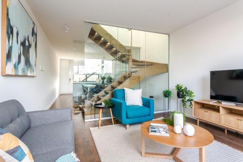 a living room with a blue couch and a staircase at Little Grenfell Apartments by Urban Rest in Rose Park
