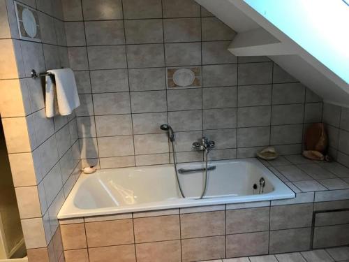 a bathroom with a bath tub in a tiled room at Lovely Meadow House in the land of Croix Scaille in Gedinne
