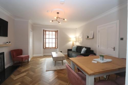 a living room with a table and a couch at Charming two bedroom, two bathroom detached cottage in Boʼness