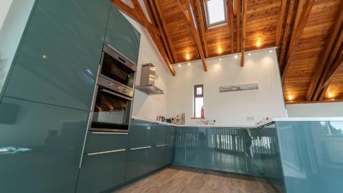 a kitchen with green cabinets and a wooden ceiling at Stylish, Spacious Sea View House in Galway