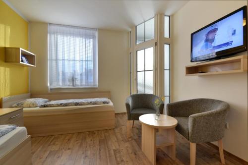 a room with a bed and two chairs and a tv at Hotel Palác in Olomouc