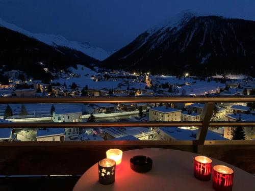 a table with candles on a balcony with a view of a town at Spectacular View & Central Location in Davos in Davos