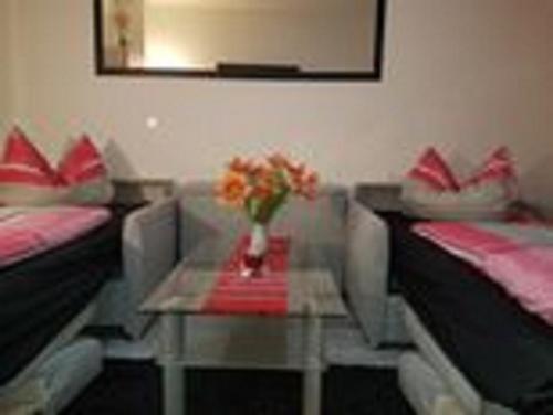 a room with two beds and a table with flowers on it at Ferienwohnungen am Krossinsee in Berlin
