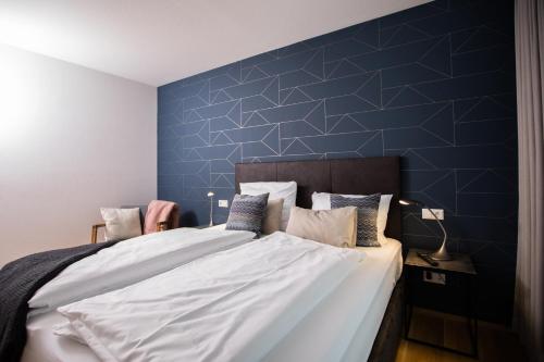 een slaapkamer met een groot bed met een blauwe muur bij Ferienwohnung Säntis in Friedrichshafen
