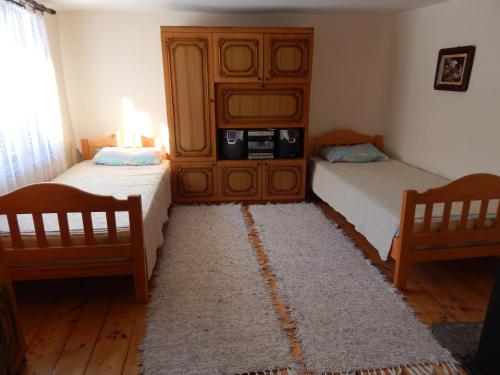 a bedroom with two beds and a cabinet and a rug at Etno kuca Nikolov in Dimitrovgrad