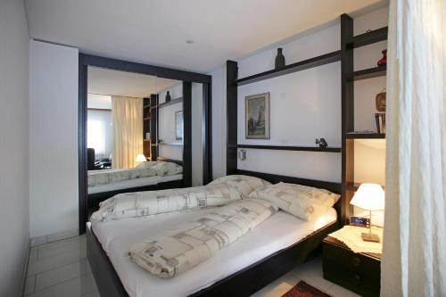- une chambre avec un grand lit et un miroir dans l'établissement Baron / Baronesse Apartments, à Loèche-les-Bains