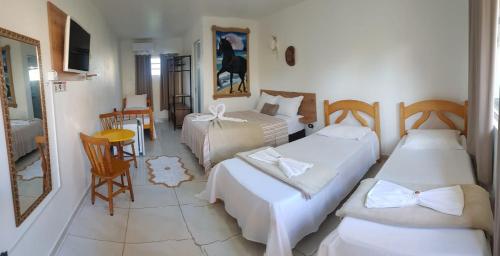 una habitación de hotel con dos camas y una mesa en Pousada Alegria do Cowboy, en Penha